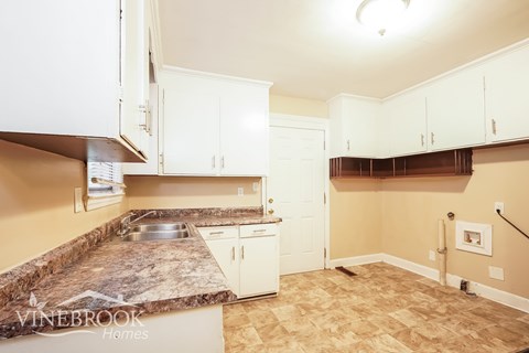 A kitchen with a granite counter top and white cabinets.