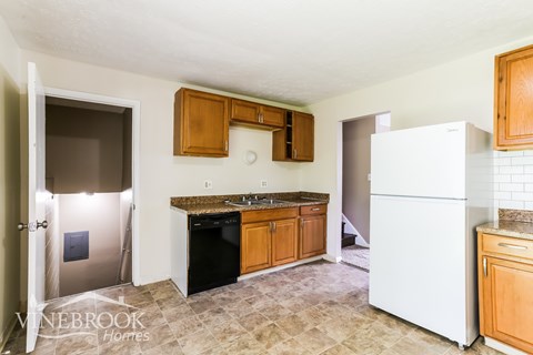 A kitchen with a white refrigerator and wooden cabinets.