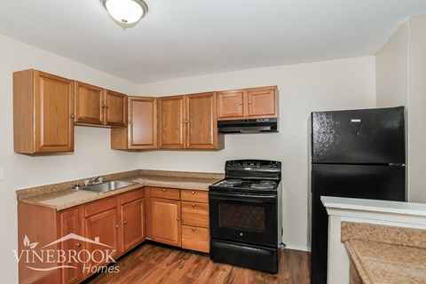 A kitchen with wooden cabinets and black appliances.