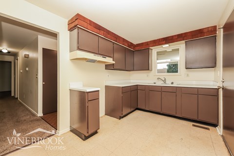 A kitchen area with brown cabinets and a window.