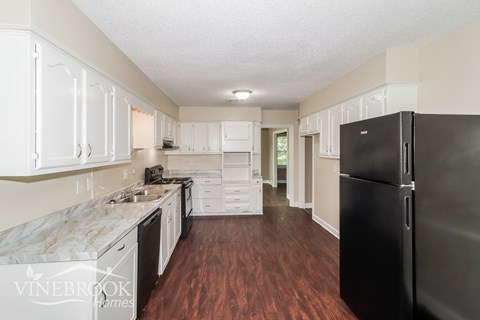 A kitchen with a black refrigerator and white cabinets.