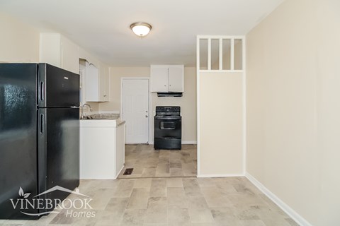 A kitchen with a black fridge and white cabinets.