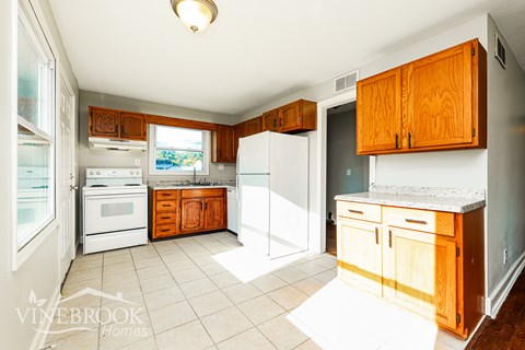 A kitchen with white appliances and wooden cabinets.