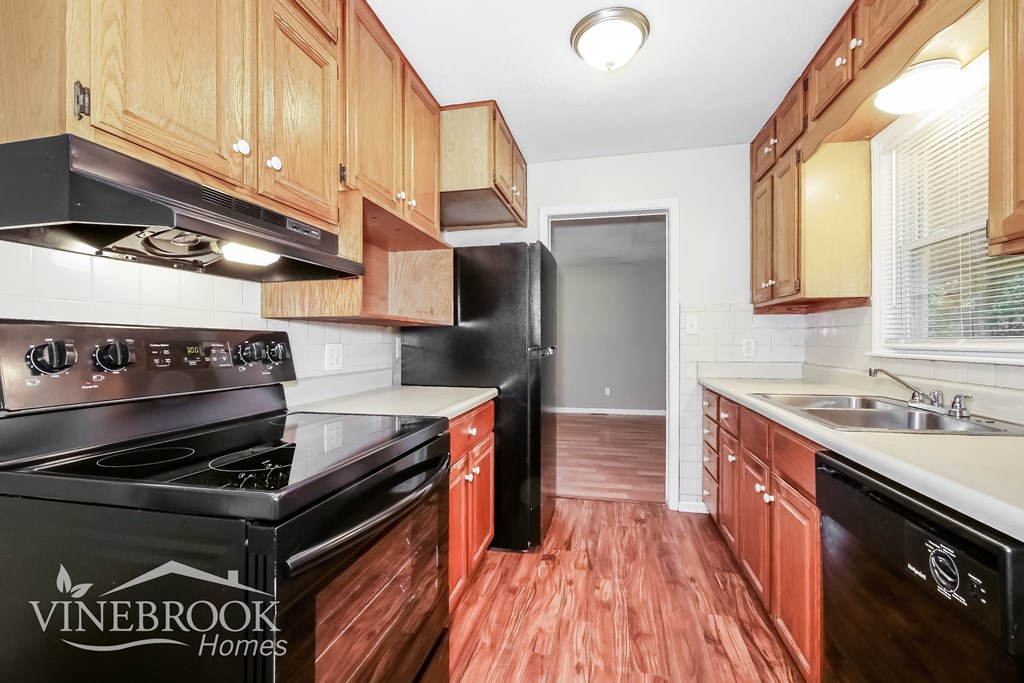 A kitchen with wooden cabinets and black appliances.