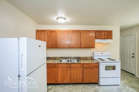 A kitchen with wooden cabinets and a white fridge.