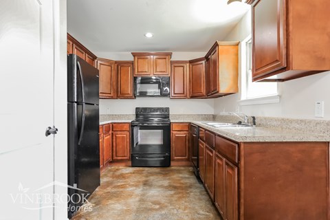 A kitchen with brown cabinets and black appliances.