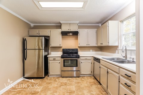 A kitchen with a refrigerator, oven, and sink.