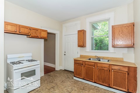A kitchen with a white stove and wooden cabinets.