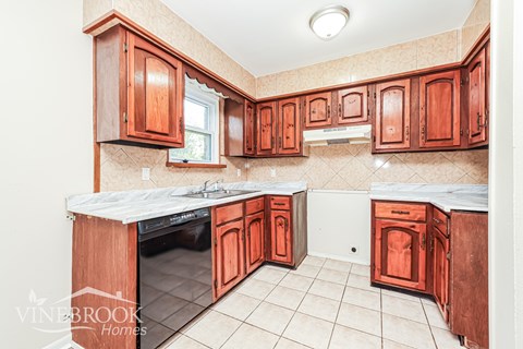 A kitchen with wooden cabinets and a white counter top.