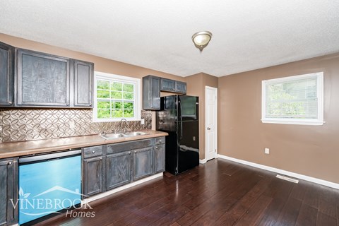 A kitchen with wooden cabinets and a black refrigerator.