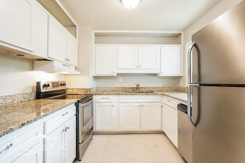 A kitchen with white cabinets and a stainless steel refrigerator.