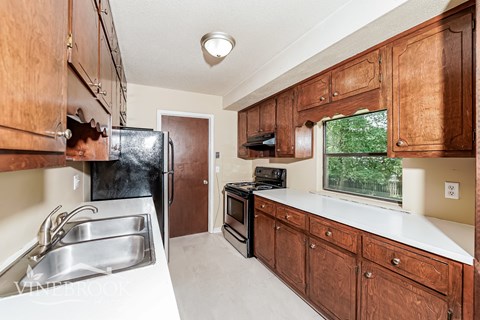 A kitchen with wooden cabinets and a black refrigerator.