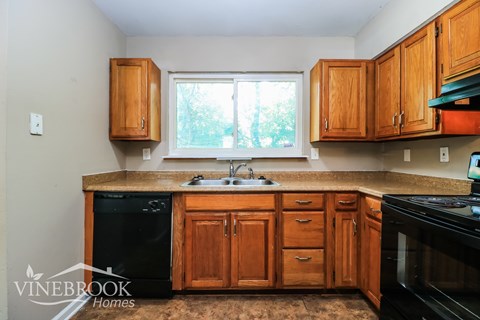 A kitchen with wooden cabinets and black appliances.