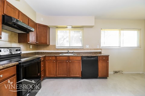A kitchen with wooden cabinets and black appliances.