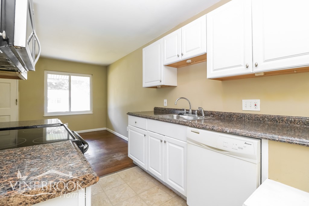 A kitchen with granite countertops and white cabinets.