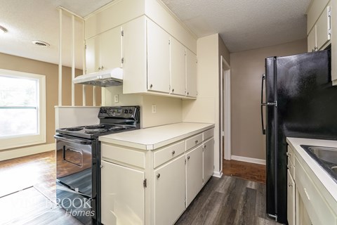 A kitchen with white cabinets and a black refrigerator.