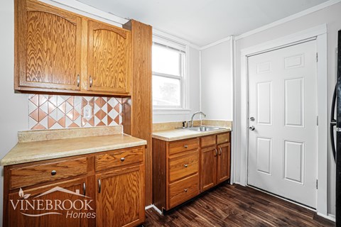 A kitchen with wooden cabinets and a white door.