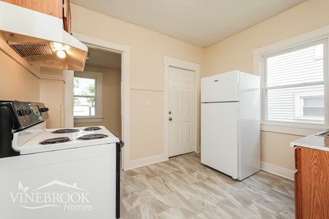 A kitchen area with a stove top oven and a refrigerator.