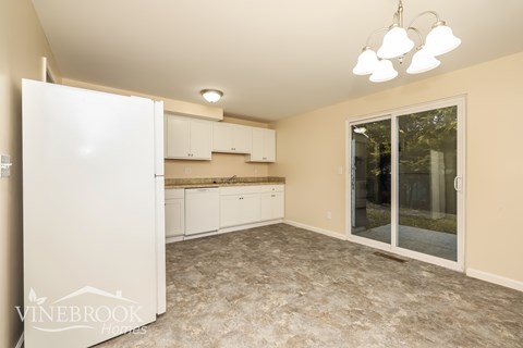 A kitchen with a white refrigerator and cabinets.