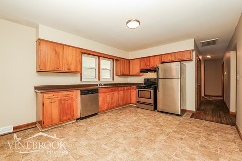 A kitchen with wooden cabinets and a tiled floor.
