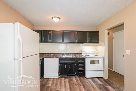 A kitchen with black cabinets and a white refrigerator.