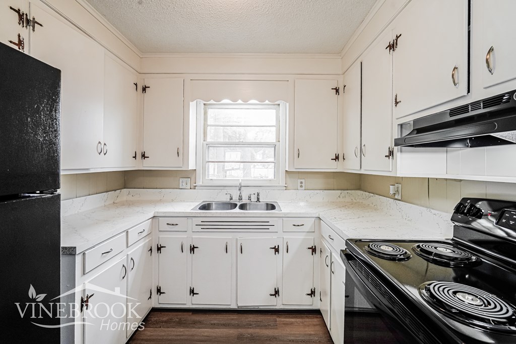 A kitchen with white cabinets and a black stove top oven.