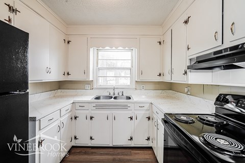 A kitchen with white cabinets and a black stove top oven.