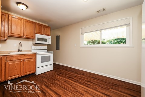 A kitchen with wooden cabinets and a white stove top oven.
