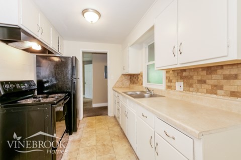 A kitchen with a black fridge and white cabinets.