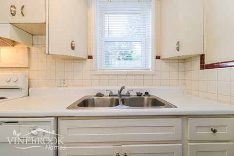 A white kitchen with a Vinebrook Homes logo.