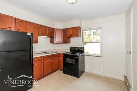 A kitchen with black appliances and brown cabinets.