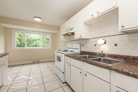 A kitchen with white cabinets and a granite countertop.