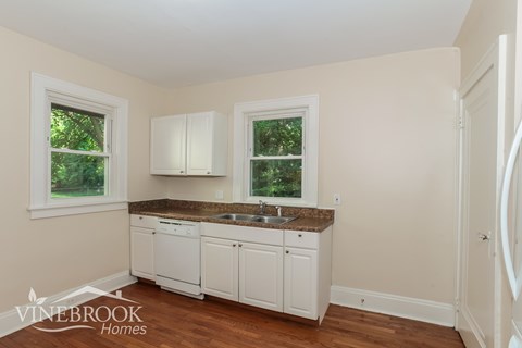 A kitchen with white cabinets and a granite countertop.