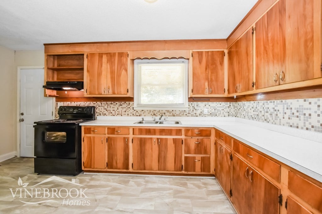 A kitchen with wooden cabinets and a black stove top oven.