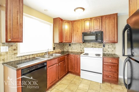 A kitchen with wooden cabinets and a black refrigerator.