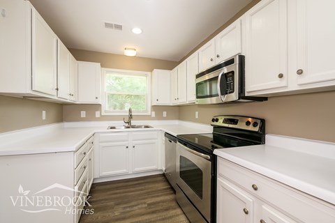 A kitchen with white cabinets and a black stove top oven.