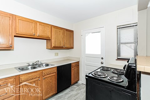 A kitchen with wooden cabinets and a black stove top oven.
