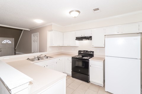 A kitchen with white cabinets and appliances.