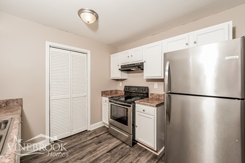 A kitchen with a stainless steel refrigerator and a stove top oven.