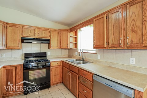 A kitchen with wooden cabinets and a black stove top oven.