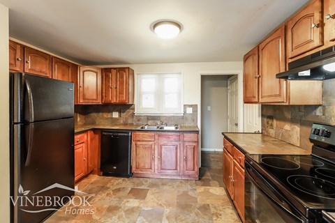 A kitchen with wooden cabinets and a black refrigerator.