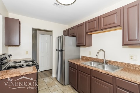A kitchen with brown cabinets and a Vinebrook Homes logo.