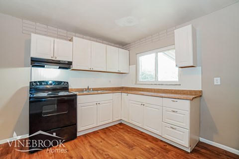 A kitchen with white cabinets and a black stove top oven.