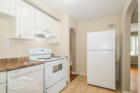 A kitchen with white appliances and cabinets.