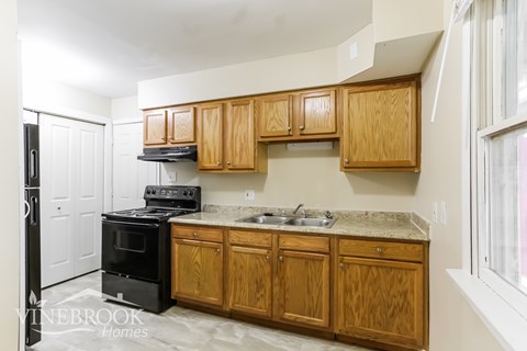 A kitchen with wooden cabinets and a black stove top oven.