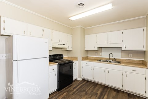 A kitchen with white cabinets and a white refrigerator.