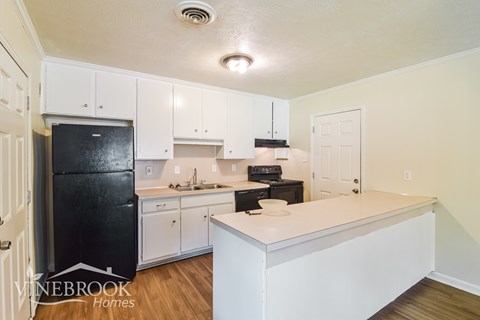 A kitchen with white cabinets and a black refrigerator.