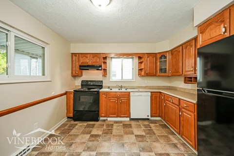A kitchen with wooden cabinets and black appliances.
