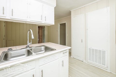 A kitchen with white cabinets and a sink.