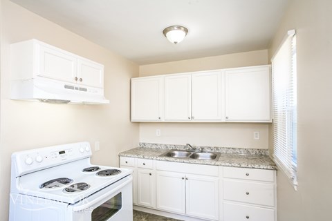 A white kitchen with a stove and cabinets.